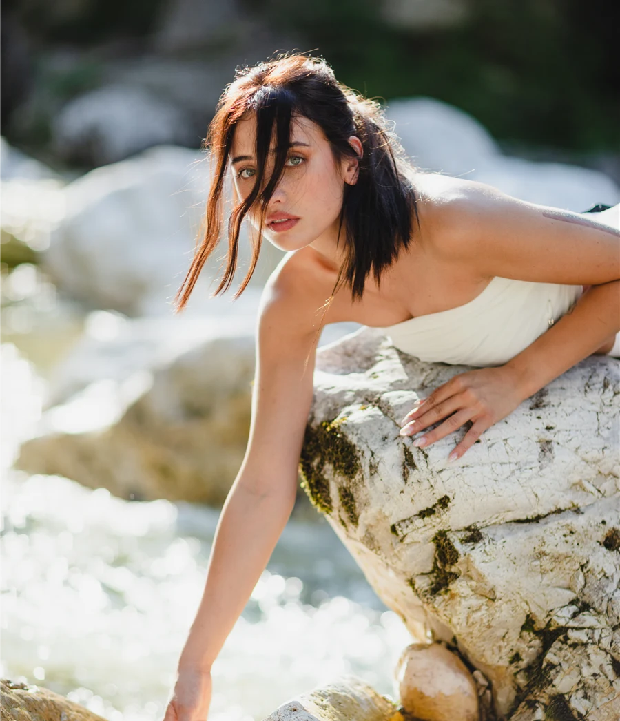 Ragazza con capelli curati vicino all'acqua, ritratto elegante